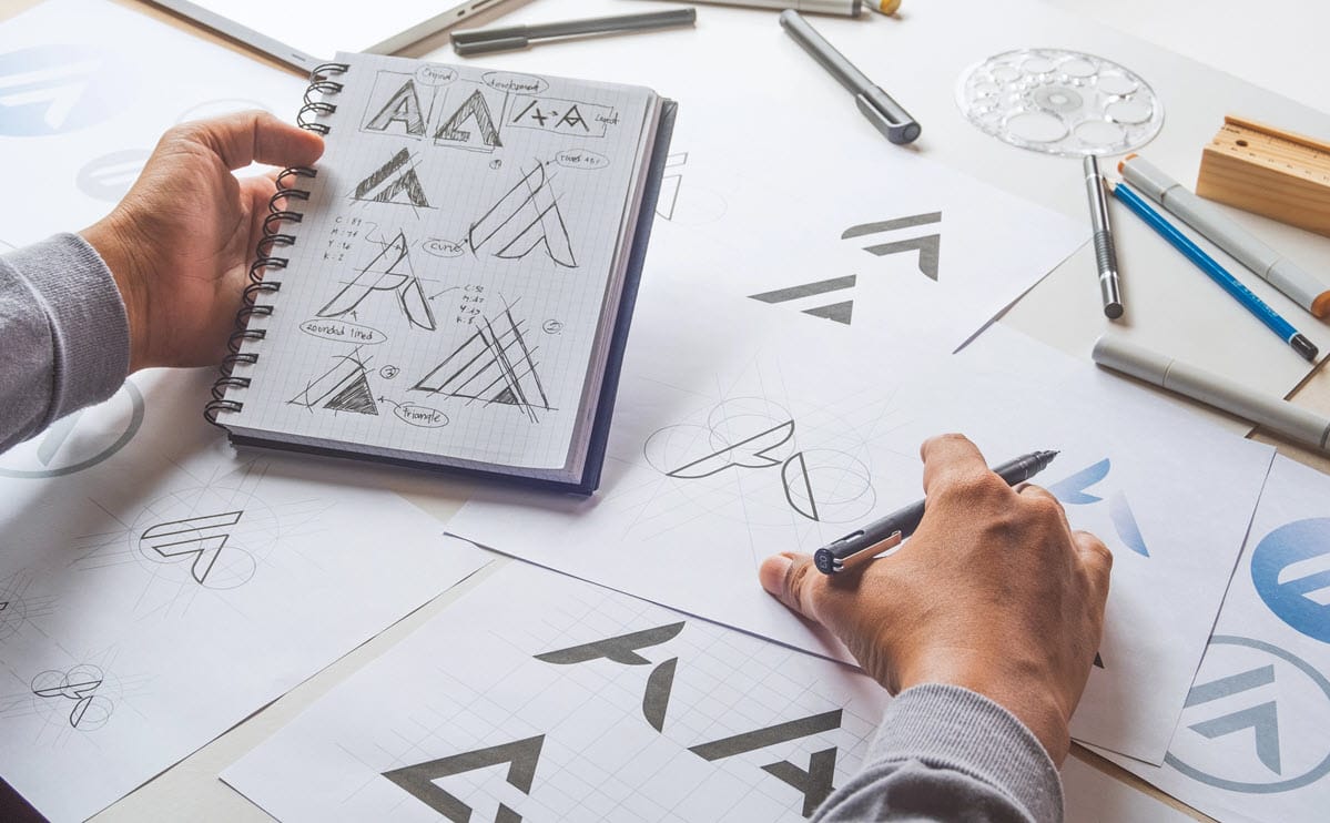 Grafiker der arbejder på skitser af et nyt logo